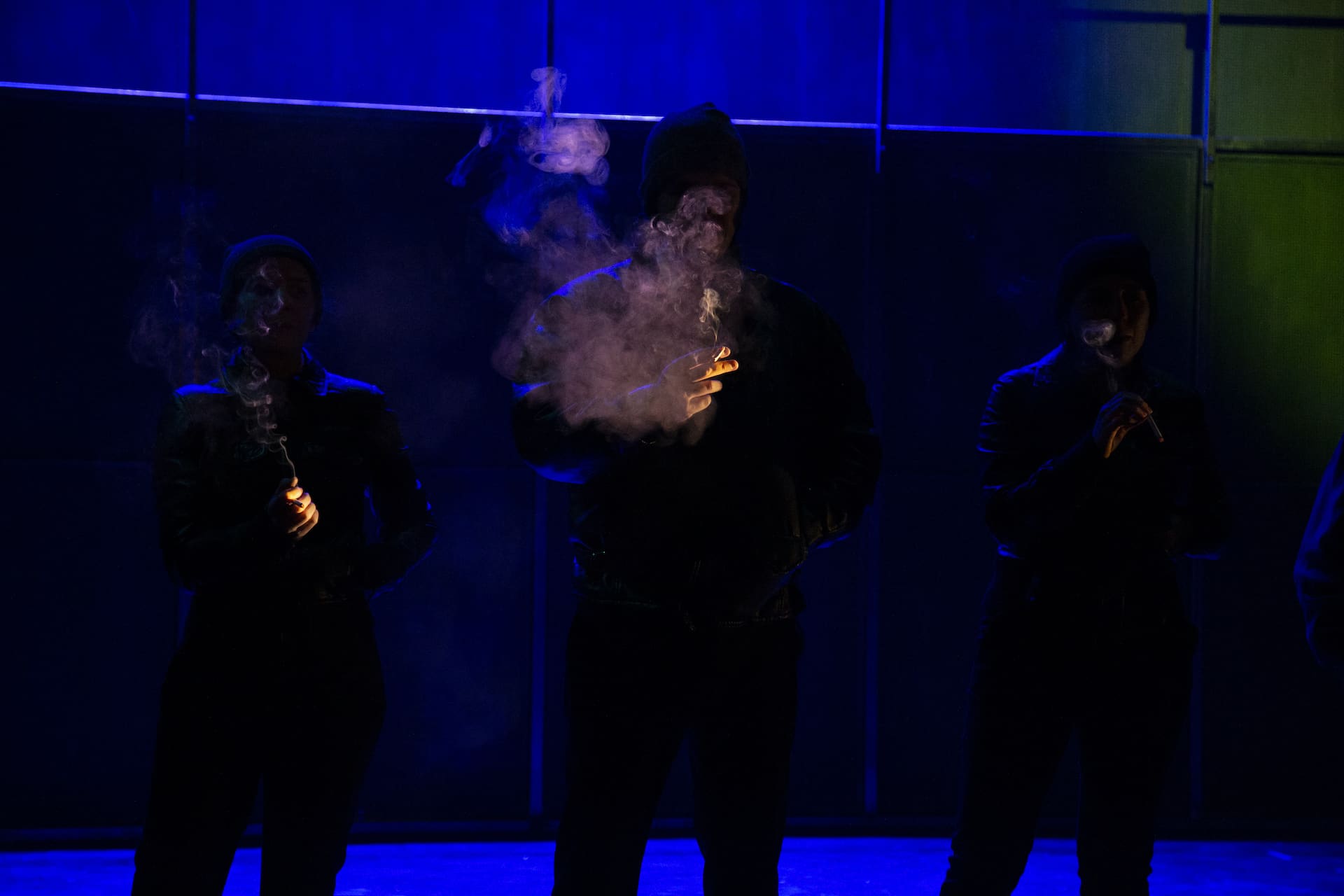 Tres persoas fumando en la penumbra, en una escena de la obra de teatro Fariña